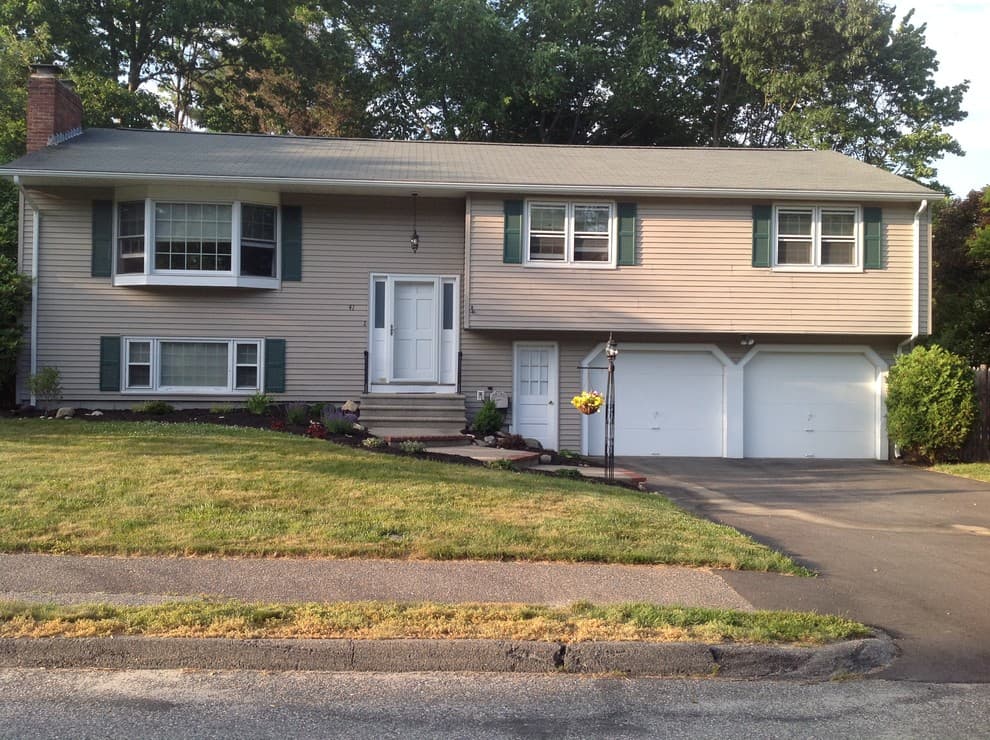 Tan raised ranch home in Connecticut with a two-car garage and green front lawn